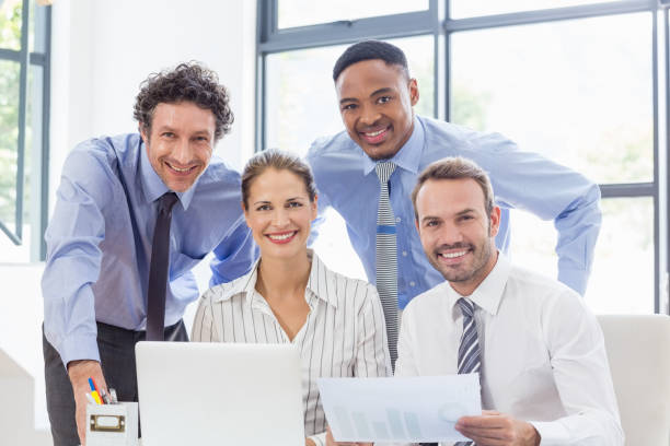 Portrait of happy business colleagues reviewing a report at desk in office